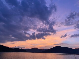 Mountains and sunset golden sky above dam reservoir while twilight time.