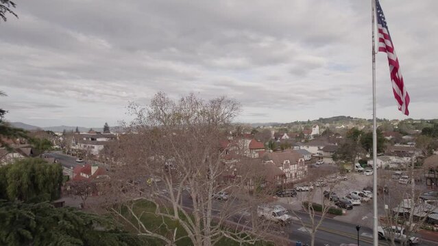 Drone view of the cityscape of Solvang with traffic on roads and houses under a cloudy sky