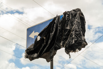 road sign wrapped with black polyethylene against the sky