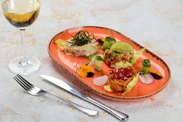 pate and spreads with microgreens on an orange plate on a white background with wine and utensils
