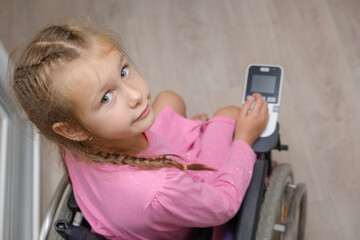 portrait of a beautiful baby girl sitting on an electric wheelchair indoors.