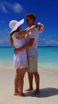 Vertical shot of a Caucasian couple hugging on the beach
