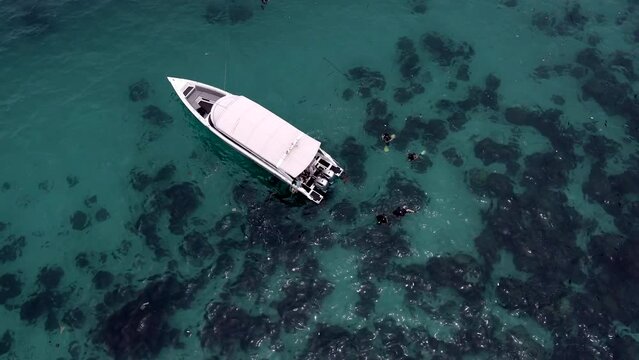 Ang Thon aerial drone film - Thailand of diving boat and divers in the water - clear shallow water - drone pulls up to show ocean shore an two boats