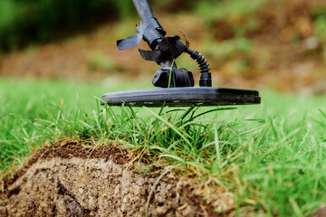 metal detector at work in the forest or field. Search for treasure and ancient values. Archeology. Man with a metal detector. Minesweeper Image. Сlose-up