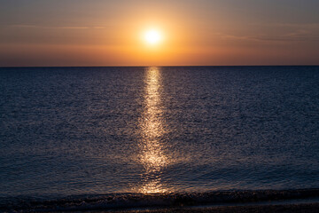 Beautiful Sunset with large yellow sun over mediterranean sea. Deep blue water and orange sky.