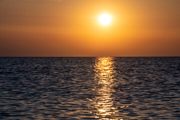 Beautiful Sunset with large yellow sun over mediterranean sea. Deep blue water and orange sky.