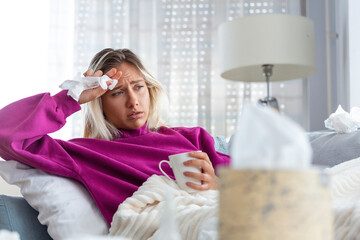 Sick woman with headache sitting under the blanket. Sick woman with seasonal infections, flu,...