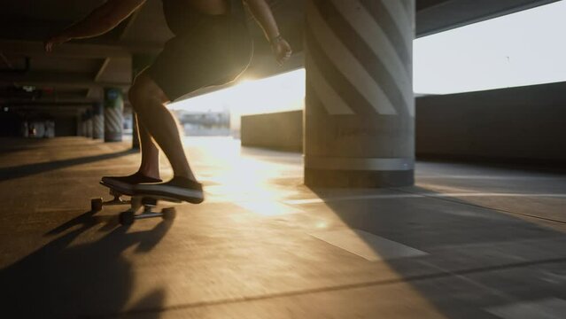 Cropped shot of the male skater enjoying of the skate board riding at the car parking