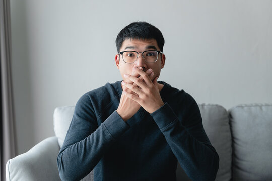 young man with shocked facial expression sitting on the sofa.