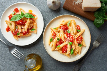 Plates of penne pasta with cherry tomatoes and fresh basil top view