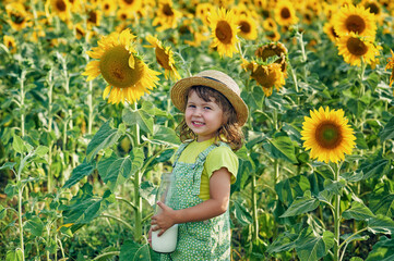 Happy little girl in a field with sunflowers. - 521367635