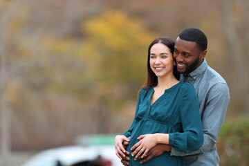 Interracial couple looking away enjoying pregnancy
