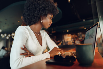 Smiling young african woman sitting with laptop in coffee shop