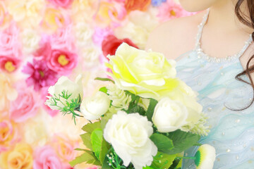 水色のドレスを着て花束を見つめる女性