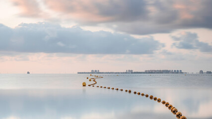 A string of buoys, stretching to the horizon of a very calm, mirror like sea, on a tranquil summer...