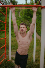 Cheerful young man standing hands up showing armpits. Athlete going to workout using horizontal bar or high bar outdoors