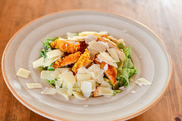 Caesar salad with lettuce,chicken ,parmesan cheese and croutons on wooden table in  a beach restaurant