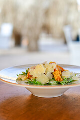 Caesar salad with lettuce,chicken ,parmesan cheese and croutons on wooden table in  a beach restaurant