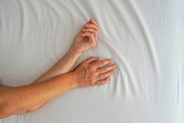 Top view woman hands grasping the bed sheet in the moment of sexual pleasure or orgasm. Woman hands...