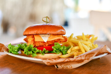 Delicious  Chicken Burger  with bacon, cheddar ,egg  and home made french fries from organic potatoes on wooden table 