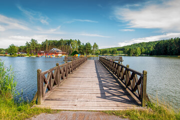 A beautiful wooden pier over the lagoon. The golden hour at the lagoon surrounded by pine forests....