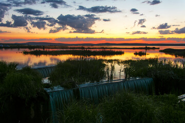 Colorful landscape calm water of a small lake in the rays of the setting sun