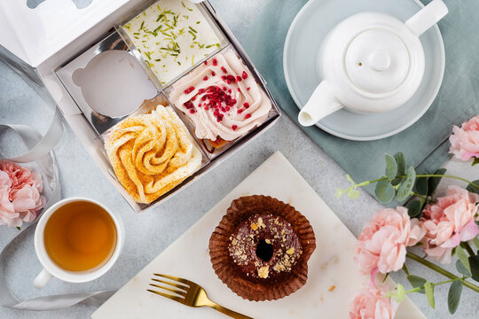 A set of desserts in a white box on a light table (trifles, cake pops) and a cup of tea. sweet concept