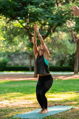 beautiful yoga teacher doing Utkatasana posture in the park