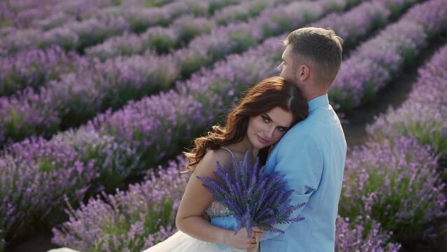 The groom tenderly embraces the bride in a lavender field