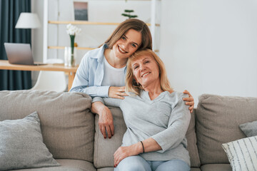 Smiling and looking at the camera. Mother and daughter is together at home