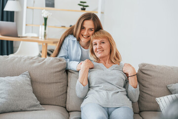 Smiling and looking at the camera. Mother and daughter is together at home