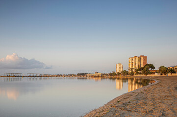 Naklejka premium High rise building, along a Spanish beach, reflecting in the calm ocean, at sunrise
