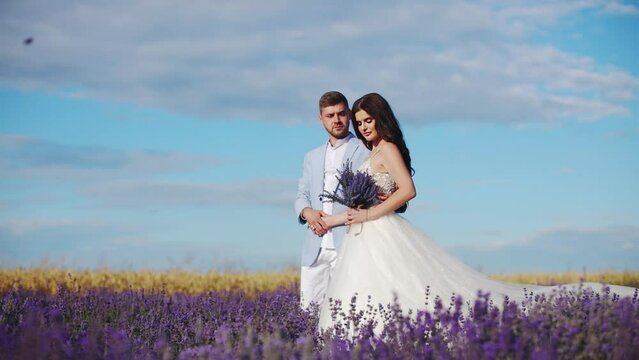 Newlyweds in love are walking through a field of lavender flowers