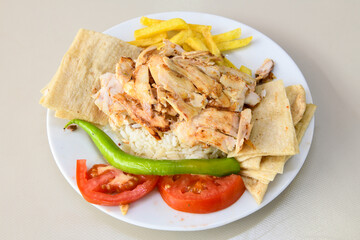 Turkish and Arabic Traditional Ramadan chicken doner kebab with tasty tomato sauce and rice or turkish pilav in white plate on wood table background. (Pilav ustu tavuk doner)