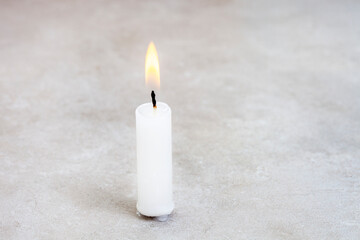 Obraz na płótnie Canvas Single burning candle with mottled grey backdrop and ample copy space