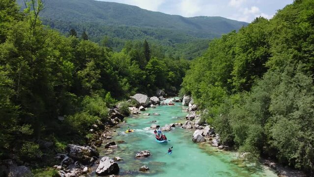 Soca Valley, Slovenia - 4K flying above the emerald alpine river Soca with kayaks and rafting boats going down the river on a bright summer day