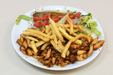 Turkish and Arabic Traditional Ramadan chicken doner kebab with tasty tomato sauce and rice or turkish pilav in white plate on wood table background. (Pilav ustu tavuk doner)