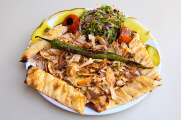 Turkish and Arabic Traditional Ramadan chicken doner kebab with tasty tomato sauce and rice or turkish pilav in white plate on wood table background. (Pilav ustu tavuk doner)