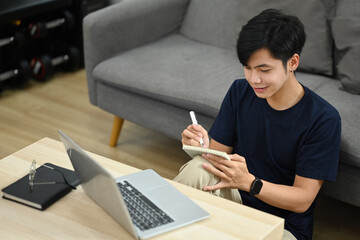 Asian male working, checking email in morning or searching information on laptop in bright living room