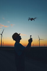 Engineer mechanic using drone for inspection in a windmill farm park.