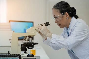 Medical Development Laboratory: Female Scientist Looking Under Microscope, Analyzes Petri Dish Sample. In Background Big Pharmaceutical Lab with Specialists Conducting Medicine, Biotechnology Research