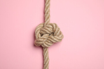 Linen rope with knot on pink background, top view. Unity concept