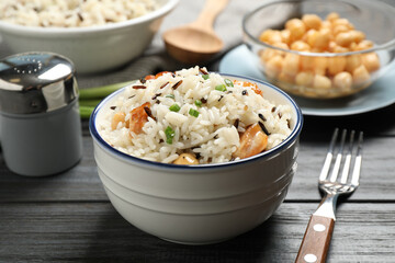 Delicious rice pilaf with chicken on black wooden table