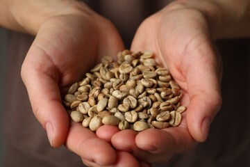 Woman holding pile of green coffee beans, closeup