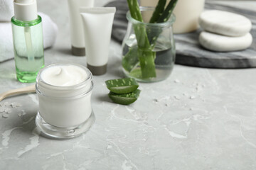 Fototapeta na wymiar Different cosmetic products and aloe on grey marble table