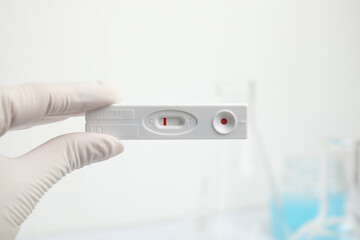 Doctor holding disposable express test for hepatitis indoors, closeup