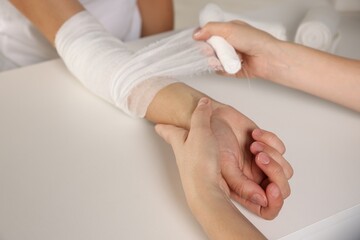 Obraz na płótnie Canvas Doctor applying bandage onto patient's arm in hospital, closeup