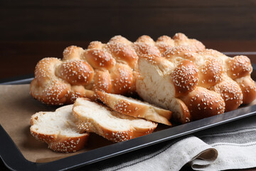 Baking tray with homemade braided bread on wooden table, closeup. Challah for Shabbat