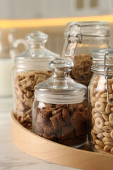Glass containers with different breakfast cereals on white marble table in kitchen