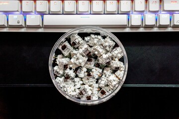 Top view of mechanical keyboard switches piled in a transparent jar